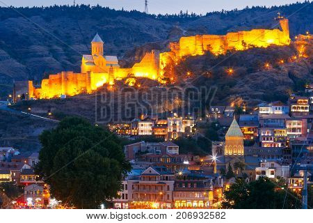 Amazing Olt town with Narikala ancient fortress with St Nicholas Church in night Illumination during evening blue hour, Tbilisi, Georgia.