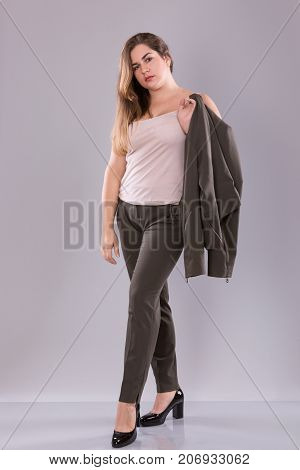 Portrait of a plus size female model posing in broun costume over grey background. Beautiful woman with curvy figure.