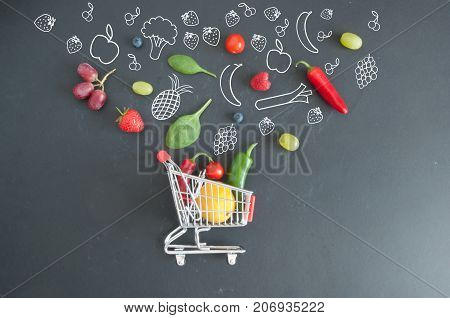 Grocery shopping cart filled with fruits and vegetables and sketches on a chalkboard