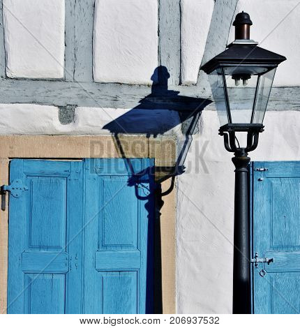 Close up of a Street lamp with its shadow on the house wall