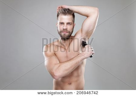 Handsome Bearded Man With A Trimmer Shaving Off Body Hair