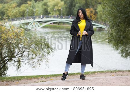 Young brunette woman in gray woolen coat on background autumn park