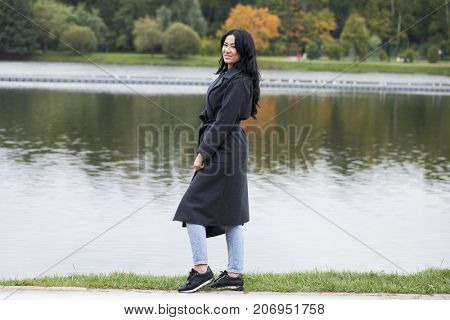 Young brunette woman in gray woolen coat on background autumn park