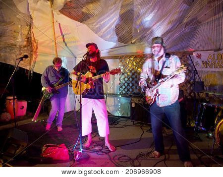 OAHU - FEBRUARY 20 2017: Rock Musicians Paul Isak and Tommy Osuna playing guitars at Optimysstique 2017 Campout under a giant sail at Camp Mokuleia on the North Shore of Oahu
