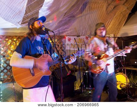 OAHU - FEBRUARY 20 2017: Rock Musicians Paul Izak and Tommy Osuna playing guitars at Optimysstique 2017 Campout under a giant sail at Camp Mokuleia on the North Shore of Oahu