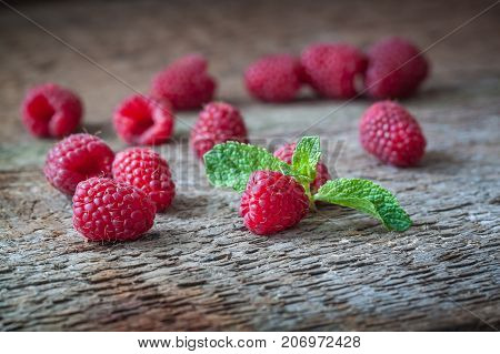 Raspberries with a mint leaf on the wooden background. Closeup.