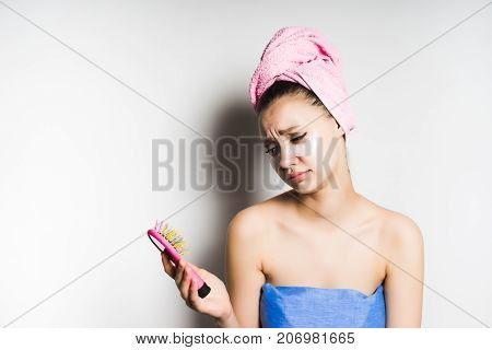 The girl in the towel looks sad at her multicolored comb