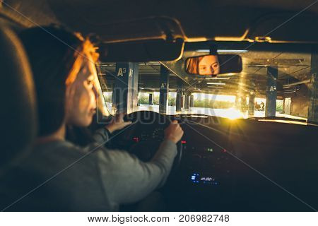 woman driving car in parking on sunset looking for spot