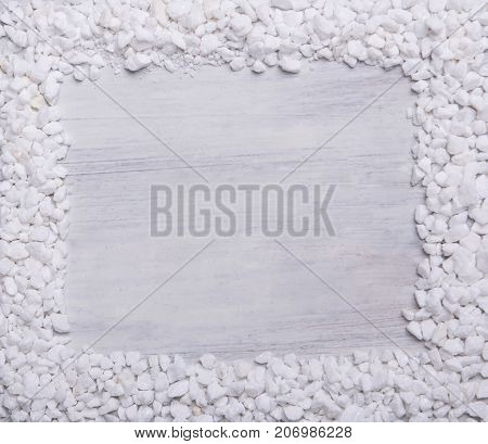 The frame from small pieces of marble on white wooden background