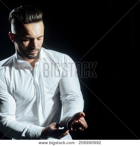 Groom buttons cufflinks on white shirt. Close up of handsome man how wears white shirt and cufflink