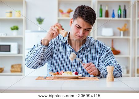 Man eating tasteless food at home for lunch
