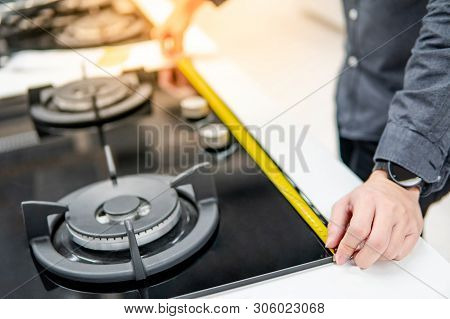 Male Hand Interior Designer Using Tape Measure On Gas Stove On Modern Countertop In Kitchen Showroom