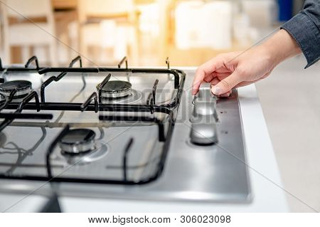 Male Hand Turning Switch Knob On Modern Gas Stove In Kitchen Showroom. Cooking Appliance In Domestic