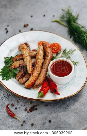 Grilled Sausages With Stewed Cabbage, With Pepper Sauce Ketchup, Chilli, Mustard On A White Plate, O