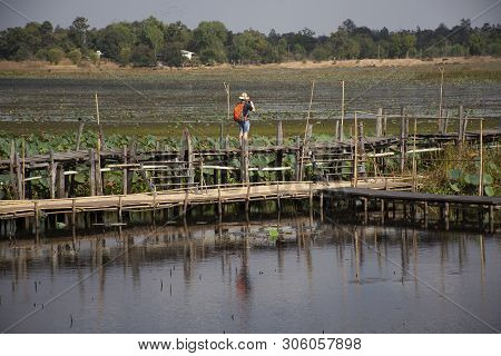 Thai People And Foreigner Travelers Travel And Walking Visit On Kae Dam Long Wood Bridge At Mahasara