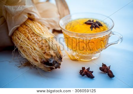 Beneficial Detoxifying Corn Tea In A Glass Cup Isolated On White Along With Some Star Anise Spice.ra