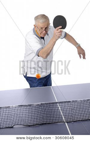 Starší muž připraven k rána ping pong míček přes síť.  Rozmáznout na míč.  Na prostřené
