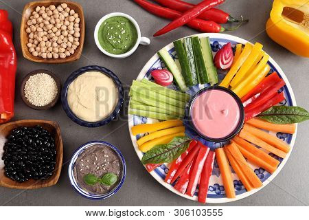 Colorful Fresh Vegetables Cut Into Strips On A Plate And Various Types Of Humus.