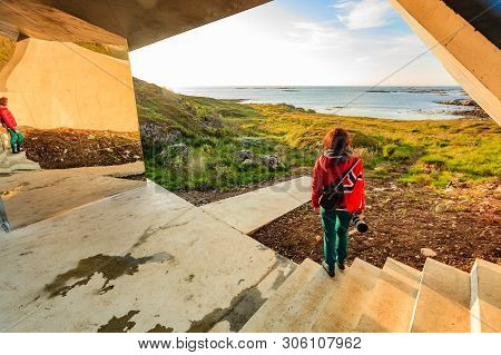Tourist Woman With Norwegian Flag Enjoying Sea Coast View From Bukkekjerka Rest Stop Area On Andoya 