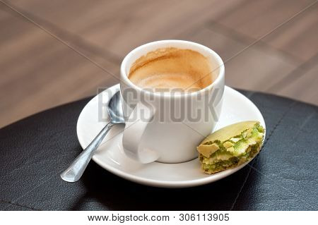 Half Full Cup Of Espresso Macchiato With Metal Spoon And Half Eaten Pistachio Macaron On Saucer. Bla