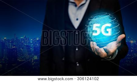 Businessman Hand Holding 5g Network Digital Hologram And Internet Of Things On City Background.5g Ne