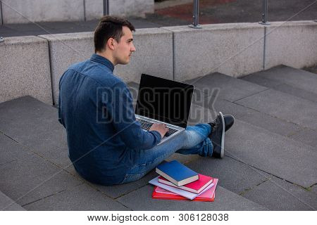 Concetrated Students Using Laptop And Books Learning For Exam On Campus Stairs. Students Looking For