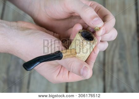 Caucasian Male Packing A Corn Cobb Pipe With Marijuana.