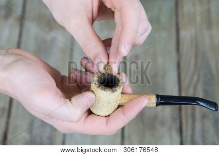 Caucasian Male Packing A Corn Cobb Pipe With Marijuana.