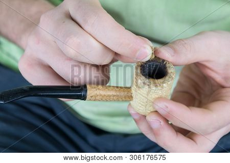 Caucasian Male Packing A Corn Cobb Pipe With Marijuana.