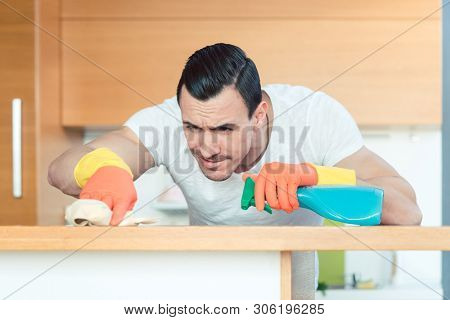 Man is very diligent dusting and cleaning the kitchen with great care