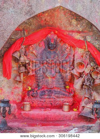Metal bells offered by devotees at Kali Temple. Shrine full of vermillion red pigment powder to worship Goddess Kali at Dhulikhel in Nepal