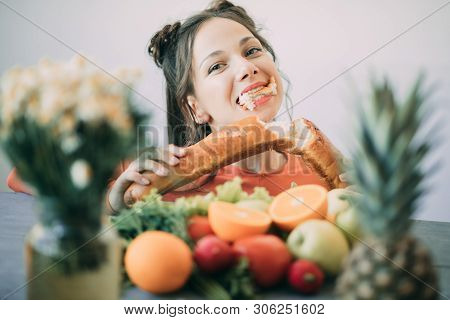 Young Woman On A Diet Succumbed To Temptation And Passionately Bites A White Crispy Long Loaf. The C