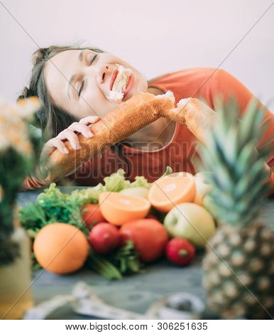 Young Woman On A Diet Succumbed To Temptation And Passionately Bites A White Crispy Long Loaf. The C