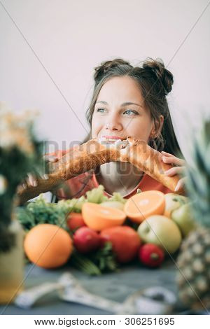 Young Woman On A Diet Succumbed To Temptation And Passionately Bites A White Crispy Long Loaf. The C