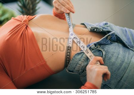 Woman Lies And Measures The Girth Around Her Waist By The Measuring Tape. The Concept Of Diet And He