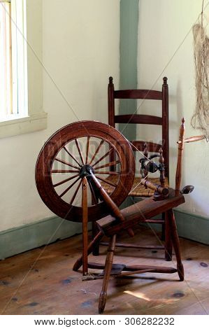 Antique Spinning Wheel Sitting In The Corner Room Of A 17th Century Home.