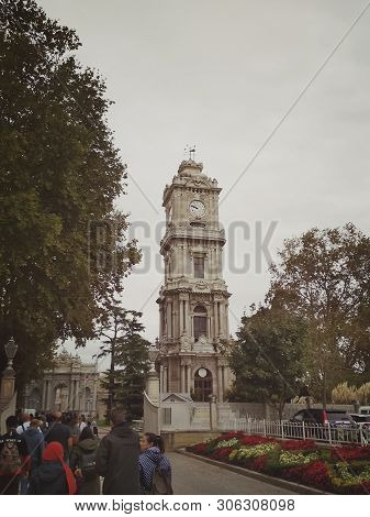 Istanbul, Turkey - September 25, 2018. A Group Of Asian Tourists Walk Past The Clock Tower Of The Do