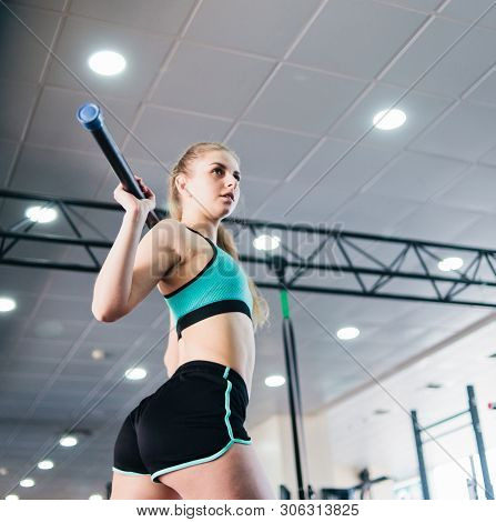 Purposeful Young Blonde Woman Doing Gymnastic Exercise With  Body Bar Stick In The Gym