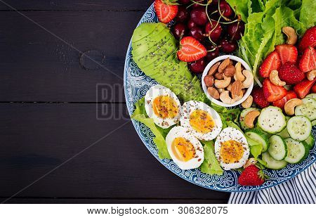 Plate With A Paleo Diet Food. Boiled Eggs, Avocado, Cucumber, Nuts, Cherry And Strawberries. Paleo B