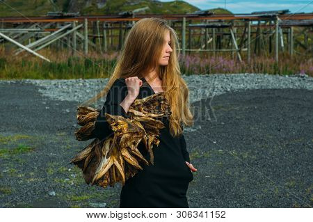 Girl In Black Dress With Bundle Of Dried Fish Heads, Lofoten Islands, Norway