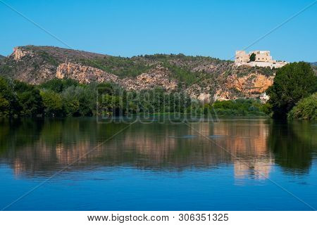 a view of the Ebro River as it passes through Miravet, Spain, highlighting its Templar castle in the top of the hill