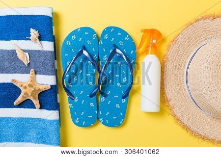 Flip Flops, Straw Hat, Starfish, Sunscreen Bottle, Body Lotion Spray On Yellow Background Top View .