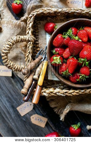Overhead Shot Of Tasty Ripe Strawberries In Wooden Bowl Stands In Wicker Strawy Basket On Rustic Tab