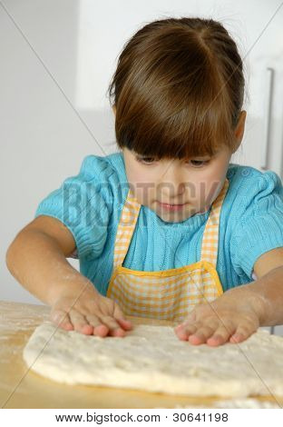 Bambina cucinare una pizza in una cucina.Ragazzino in una cucina.