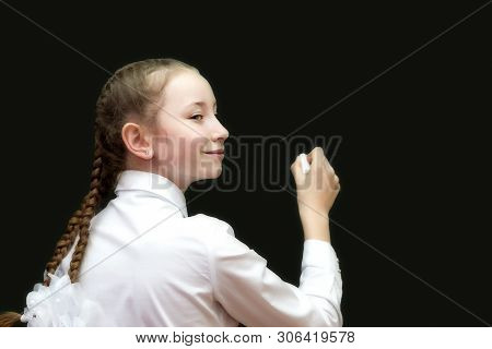 Schoolgirl Teen With Chalk On A Blackboard Writes Solution To The Problem. A Girl Of 10-12 Years Old