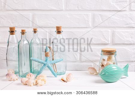 Seaside Living Decorations Near By White Brick Wall. Decorative Fish And Sea Star, Blue Bottles With