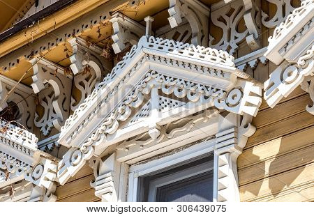 Russian Traditional Wooden Architecture. Facade Of An Old House Decorated With Wooden Carvings, Plat