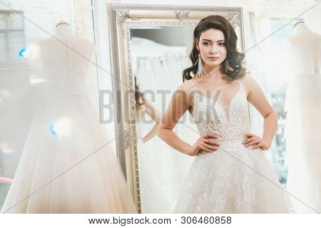 Beautifu bride choosing wedding dress in a wedding salon