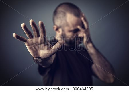 Desperate man with hand on his face and another hand leaning forward to protect himself.