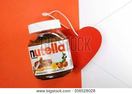 Kyiv, Ukraine - May 27, 2019: Nutella introduced to the market in 1964 by Italian company Ferrero. Nutella hazelnut on white and red background